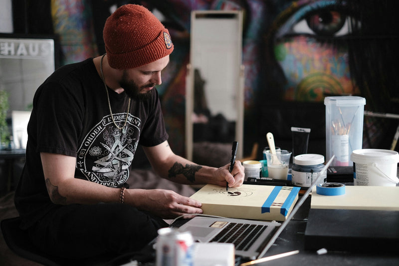 Editorial photograph of an artist drawing at a studio workbench