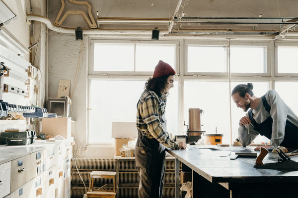 Two craftspeople collaborating at a workbench
